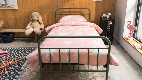 een bed met roze lakens en een knuffeldier