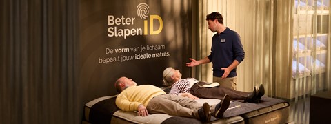 Een man die naast een paar mensen op een bed ligt