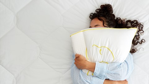 Een vrouw die in bed met een hoofdkussen ligt