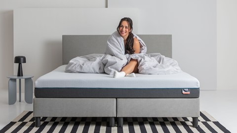 Een vrouw die op een bed zit