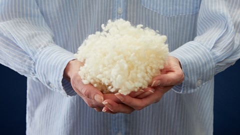 een persoon die een stapel pluizige witte wol vasthoudt