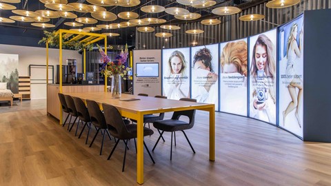 een lange tafel met stoelen voor een grote poster