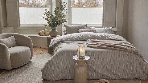 een bed met kussens en een lamp in een kamer met ramen
