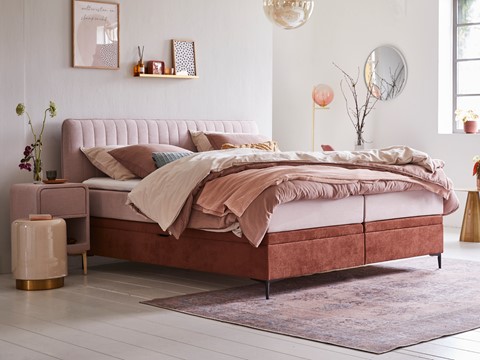 een bed met roze en bruin beddengoed