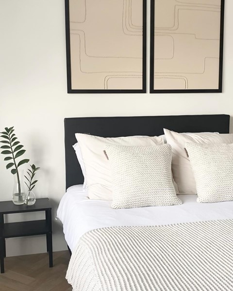 een bed met kussens en een plant aan de zijkant