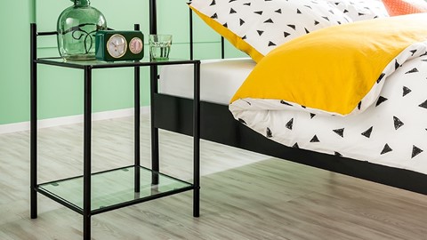 een bed met kussens en een klok op een glazen tafel