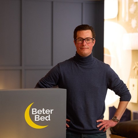 Een man die zich naast een bed bevindt