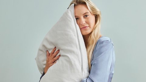 Een vrouw die een kussen houdt