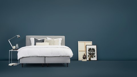 een bed met kussens en een foto aan de zijkant