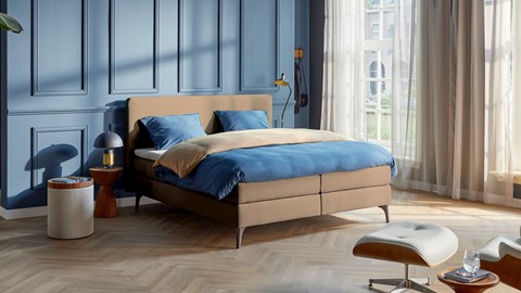 Beige boxspring in blauwe slaapkamer