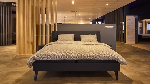 een bed met kussens en daarachter een muur