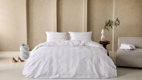een bed met een wit en oranje gestreept beddengoed