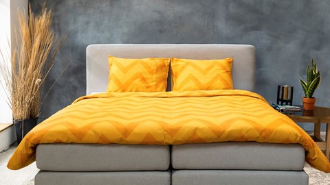 een bed met gele lakens en kussens