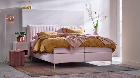 Een roze bed met een roze hoofdeinde