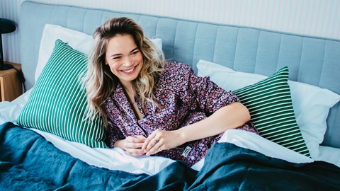 Een vrouw die in bed glimlacht