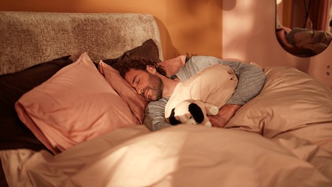 Een man die in bed slaapt met een knuffeldier