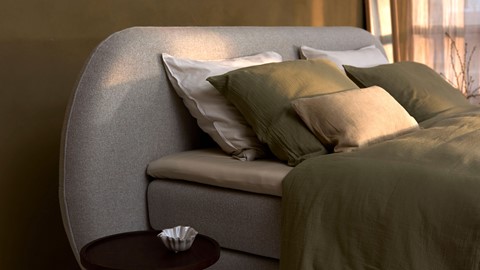 een bed met kussens en een klein tafeltje