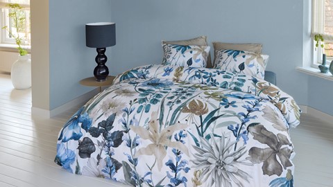 een bed met een bloemendekbed en een lamp