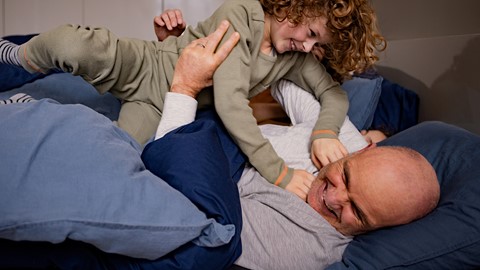 Een man en een kind spelen in bed