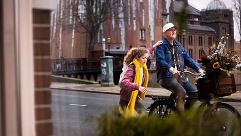 Een man en een meisje die een fiets op een straat berijden