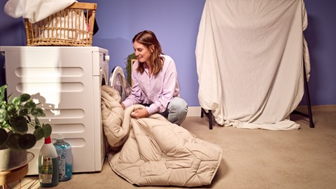Een vrouw die een deken op een wasmachine legt