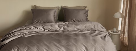 een bed met bruine lakens en kussens