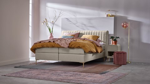 een bed met een roze deken en een roze kleed