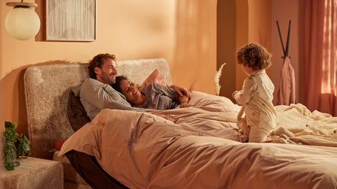 Man en vrouw relaxen op bed met kindje