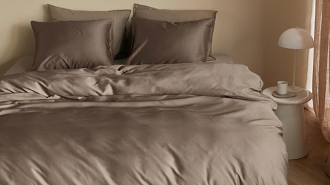 Satijnen taupe dekbedovertrek op bed in slaapkamer
