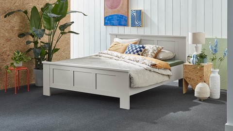 een bed met kussens en een plant ervoor