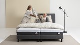 Een man en een vrouw die met kussens op een bed spelen