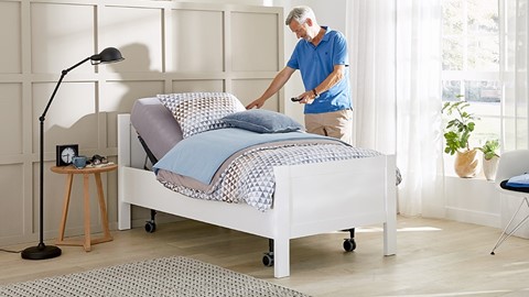 Een man die zich naast een bed bevindt