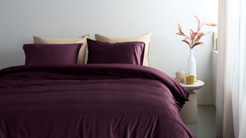 een paarse bedding met een vaas bloemen