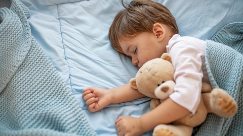 Een kind dat met een teddybeer slaapt