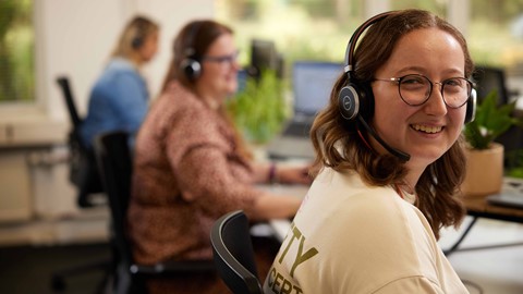 Een vrouw die hoofdtelefoons draagt en glimlacht