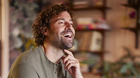 Een man met krullend haar lachend