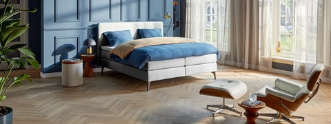 een bed met blauwe lakens en een stoel in een kamer