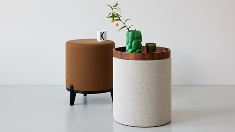 Een ronde witte en bruine cilindertafel met daarop een groene plant