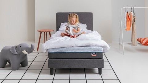 Een meisje dat een boek op een bed leest