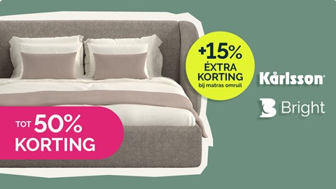 een bed met kussens en een roze-wit dekbed