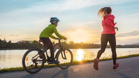 Man aan het fietsen en vrouw aan het hardlopen