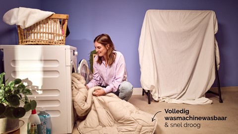 Een vrouw die een deken in een droger stopt