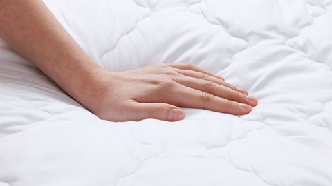 Een hand op een wit bed