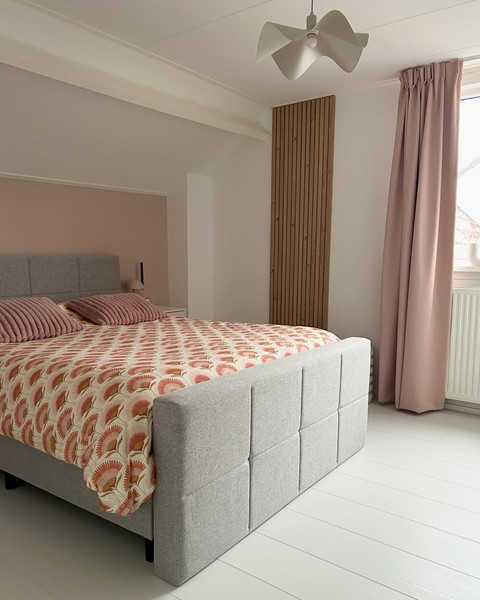 een bed met een witte vloer en roze gordijnen