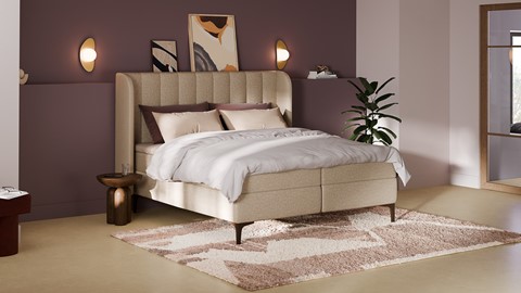een bed met een wit bedframe en een plant op een kleed