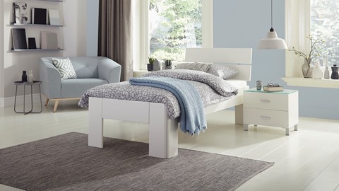 een bed met een blauwe deken en een blauwe stoel in een kamer
