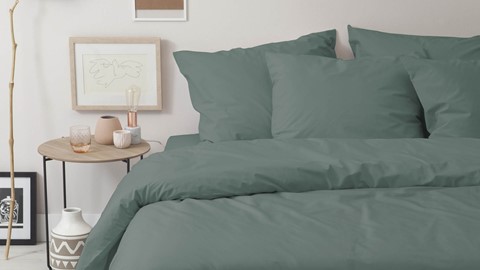 een bed met kussens en een foto op het bijzettafeltje