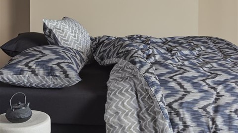 een bed met een blauw-wit dekbed