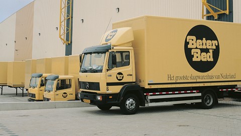Een gele vrachtwagen stond geparkeerd voor een gebouw