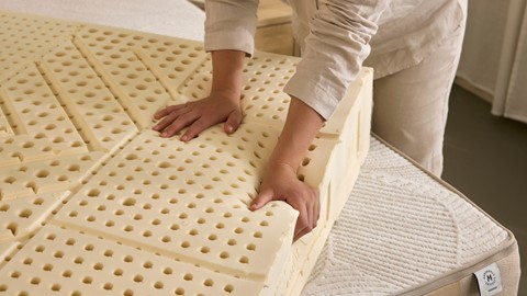 De handen van een persoon op een grote witte matras